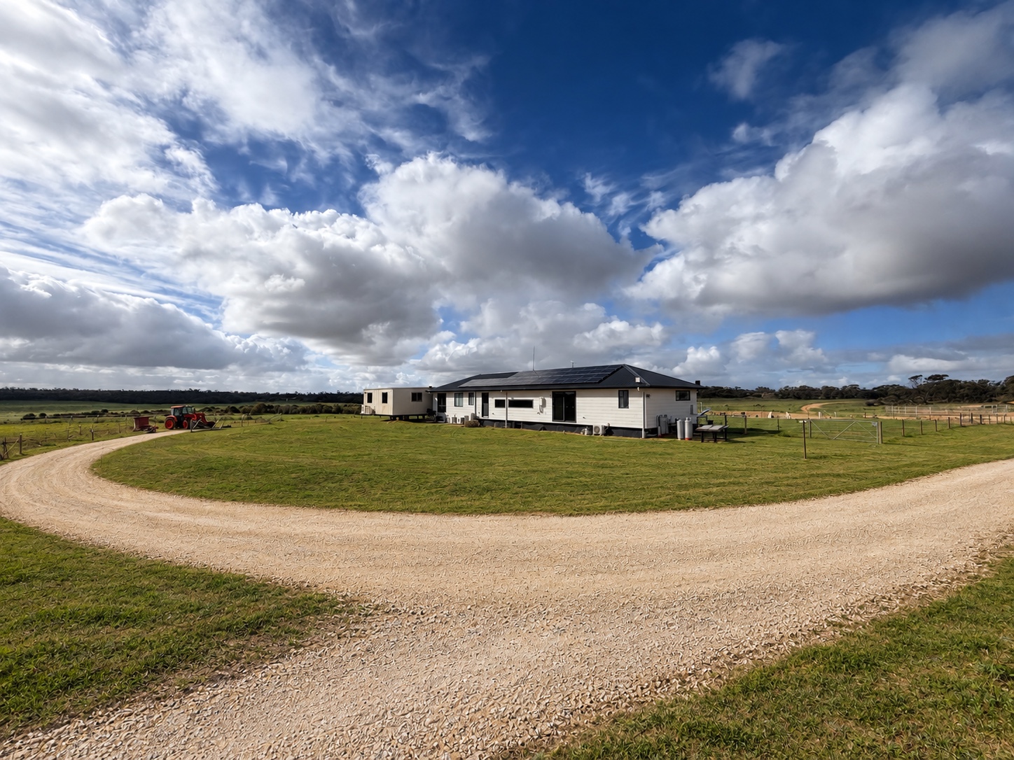 Wide view of the four-bedroom home, curved driveway and surrounding land